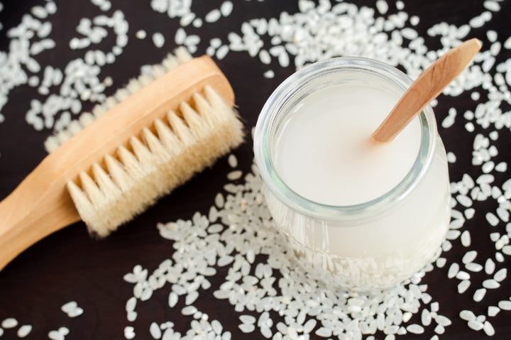 a jar containing rice water and a brush is kept on a table